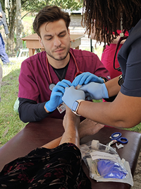 VCOM students treat a patient's foot while in Honduras.