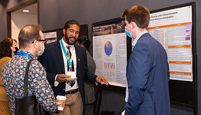 Three men discussing a poster at conference