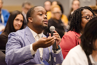 EL26-home2 Black Man with microphone asking speaker a question.