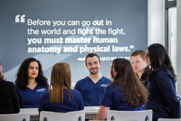 Students in blue scrubs sitting around a table