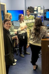 A group of students at VCOM Auburn work together in a high-tech learning environment with computer monitors.