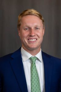 A professional headshot of a smiling man in a suit, a student from VCOM Carolinas.