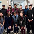 Agroupofstudentposeinthehallwayofaresearchlab