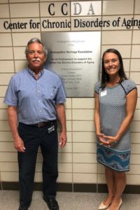 A man and a woman stand in front of a sign reading 