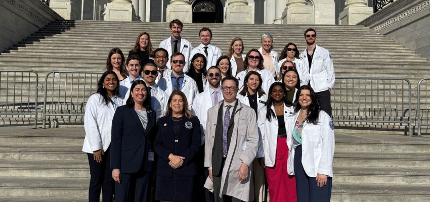 A group of medical students and faculty pose on the steps of the U.S. Capitol during a legislative advocacy visit.