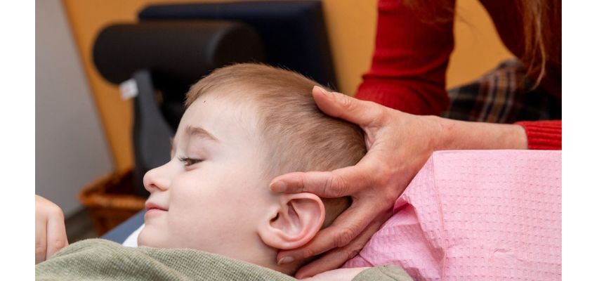 A young child receives a gentle osteopathic treatment while lying on a table.