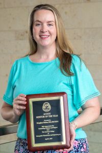 A woman holds a plaque reading