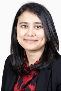 A woman in business attire smiles for a headshot with a white background.