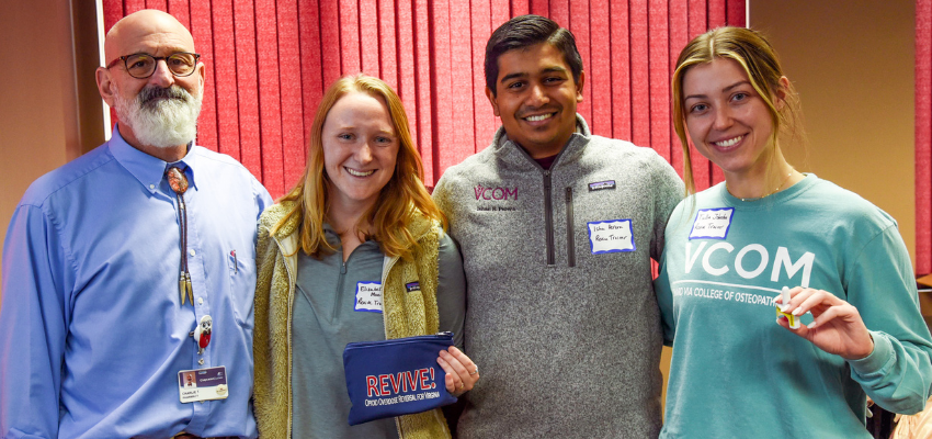 Three students smiling with faculty member