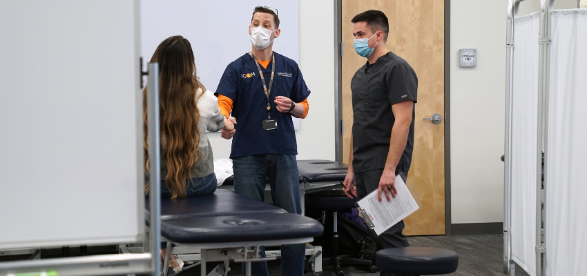 Student and doctor discuss treatment around OMM table