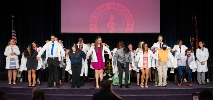 Students line up to receive white coat on stage