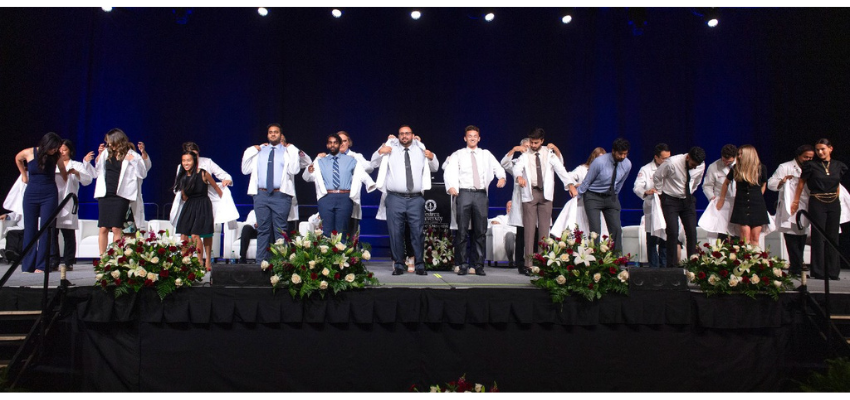 Students receive white coats on stage