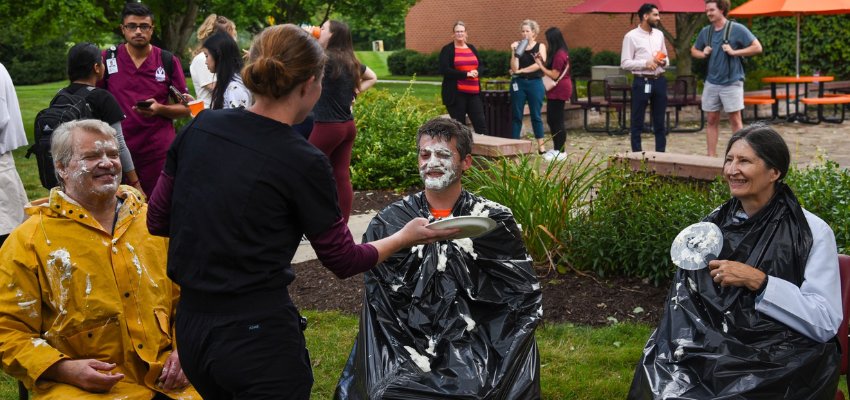 Student prepares the smear whipped cream on a faculty member