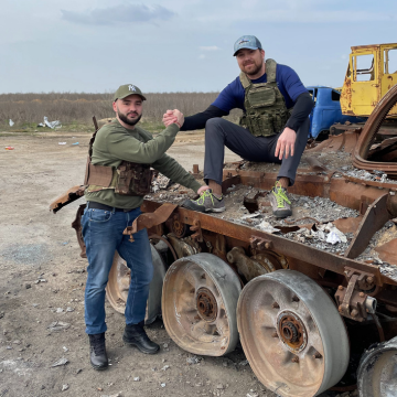 Doctor clasps hands with Ukrainian transporter sitting on broken tank