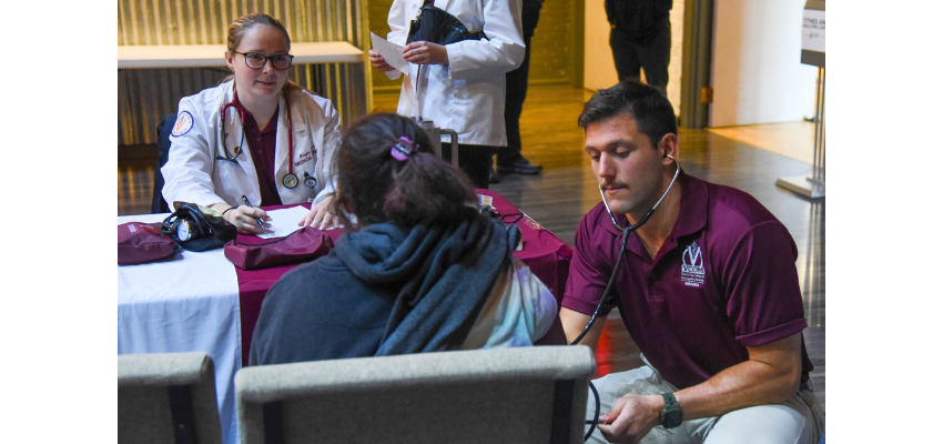 Student doctors listen to patient's heartbeat and take notes