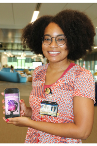 Jada holds her phone with cover image of her book
