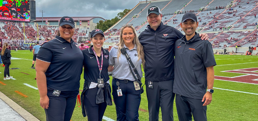 Five VCOM Virginia faculty members standing on the Virginia Tech football field