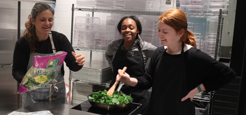 Students listen to an instructor while simmering greens