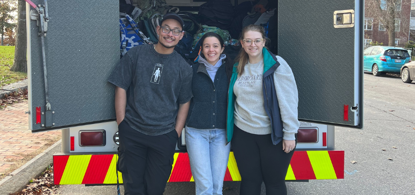 Three students stand in front of an ambulance