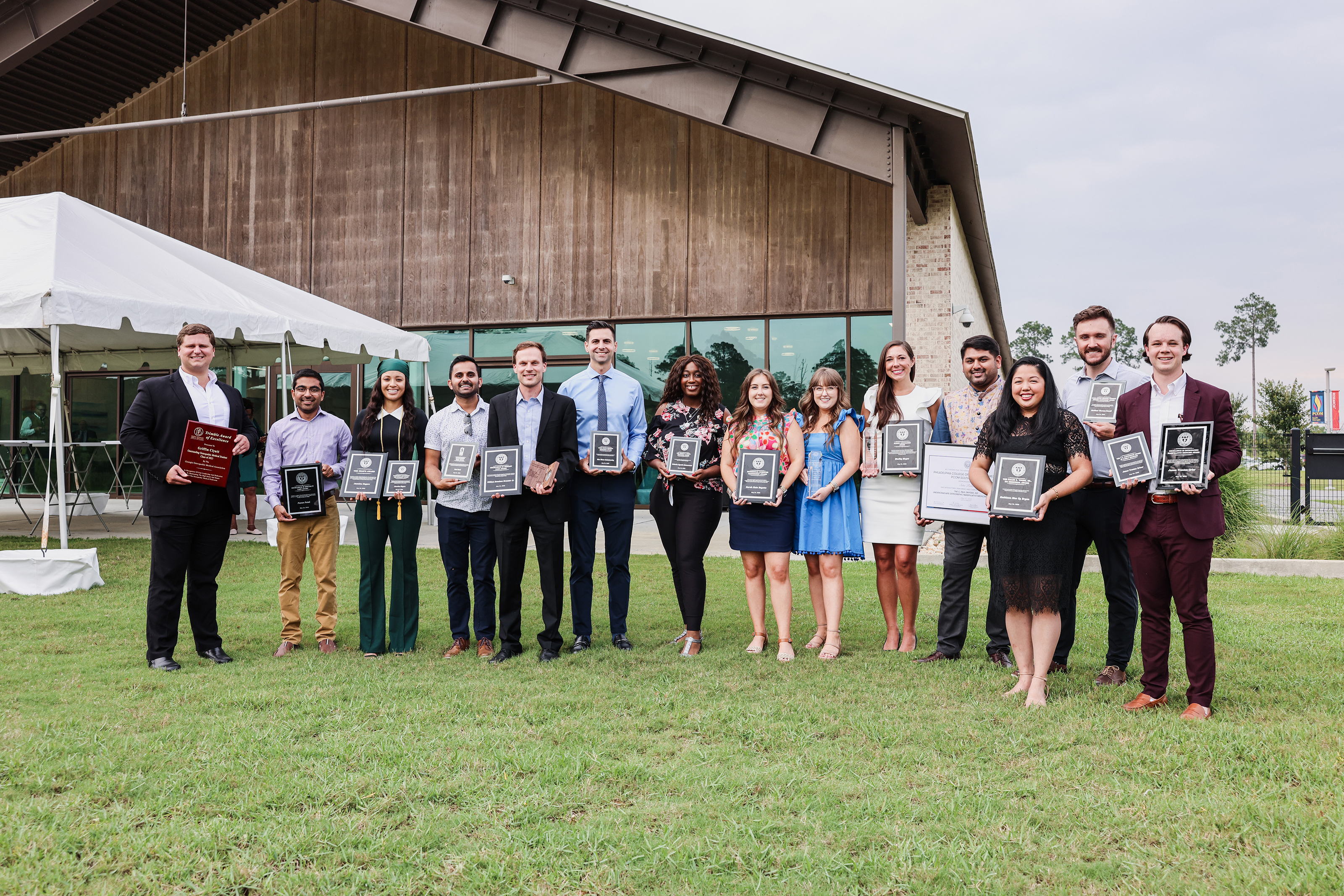 Students standing outside with plaques