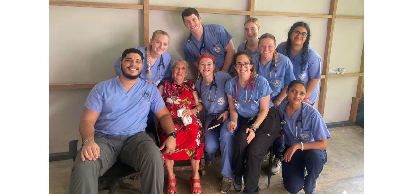 Medical students from LMU-DCOM smile alongside an elderly woman during a community outreach event.