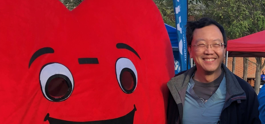 Dr. Yeung standing with heart mascot