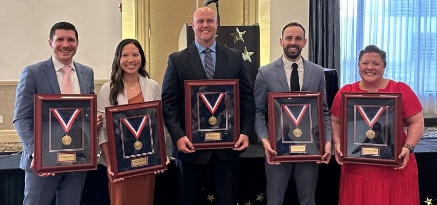 Five recipients standing with their medals