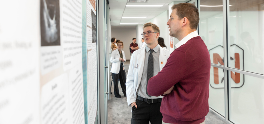 Student discusses research poster with faculty member