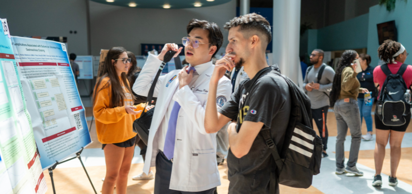 Medical students discussing research posters at PCOM Georgia.