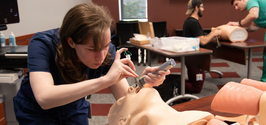 VCOM Carolinas student performing a procedure on a medical dummy.