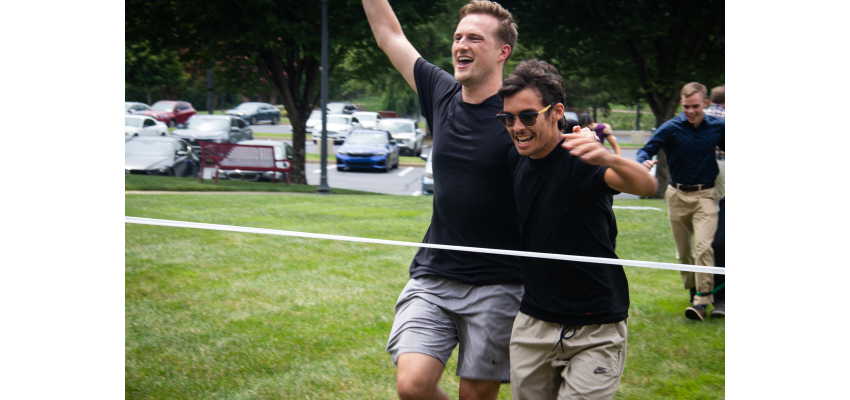 Two students from crossing the finish line in an outdoor relay race, celebrating their victory.