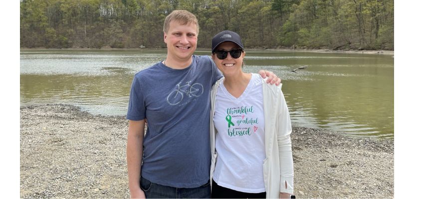 A couple posing by a lakeside during an outdoor excursion.