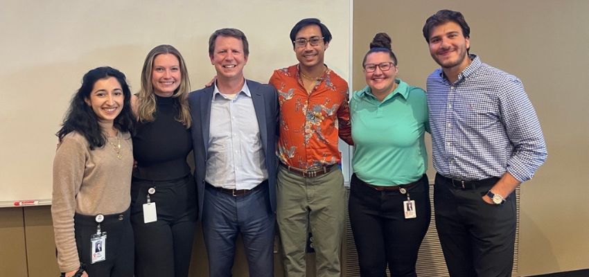 A group of students and a faculty member at VCOM-Carolinas pose together for a photo in a lecture hall.