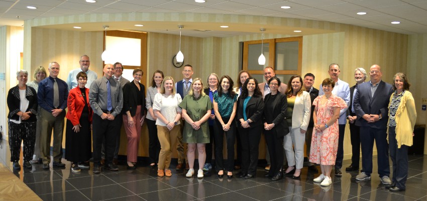 A group of medical leaders stand in a well-lit entryway.