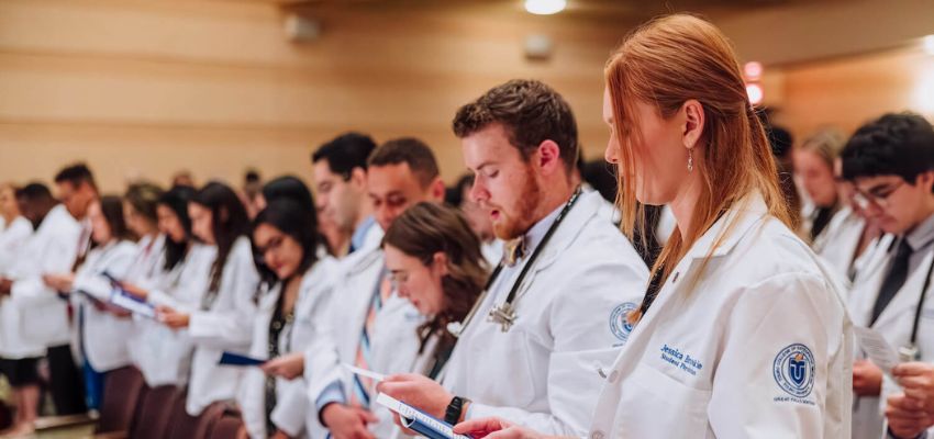 Group of medical students in white coats read aloud.