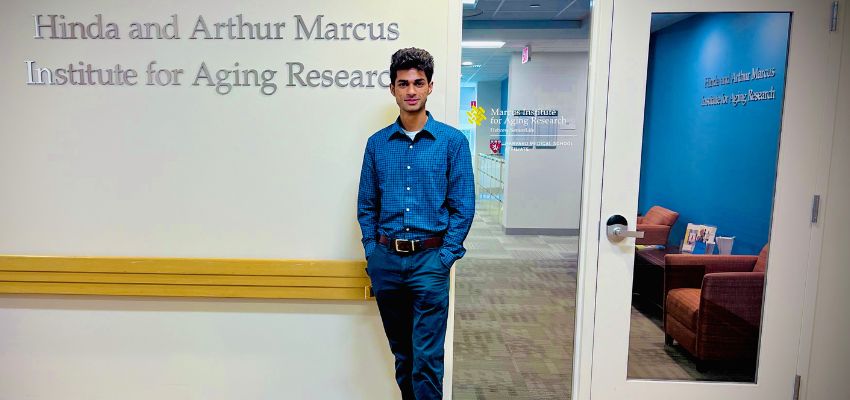 Medical student stands in front of the Hinda and Arthur Marcus Institute for Aging Research entrance.