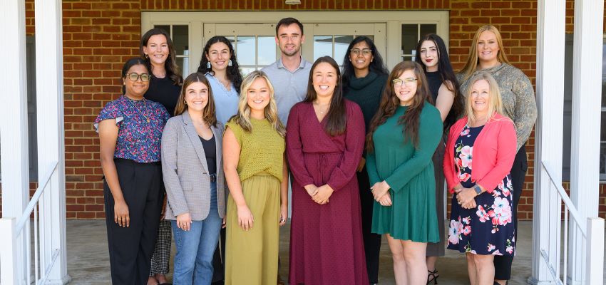 Group photo of diverse medical students smiling in front of a brick building.