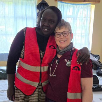 Two medical volunteers share a moment of camaraderie at a healthcare event.