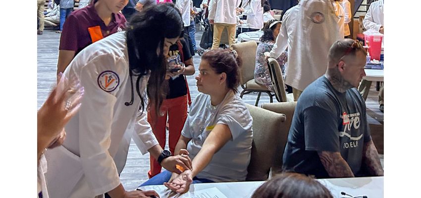 A medical student checks a patient's pulse during a community health fair.