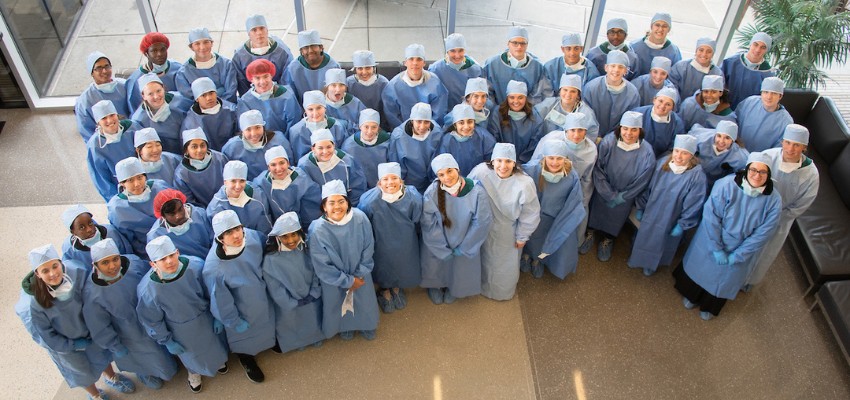 Large group of students in surgical scrubs posing together for a group photo.