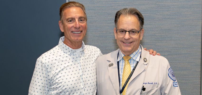 Two male doctors, one in a lab coat, smiling and standing side by side at a medical conference.