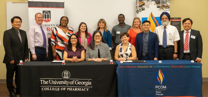 A group of medical professionals from the University of Georgia College of Pharmacy and PCOM South Georgia standing together at a collaborative event.