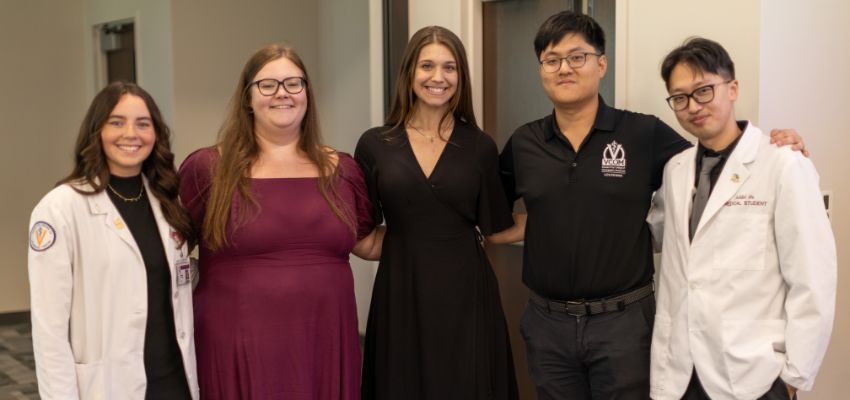 A group of five medical students and professionals posing together at a medical event, representing diverse medical institutions.