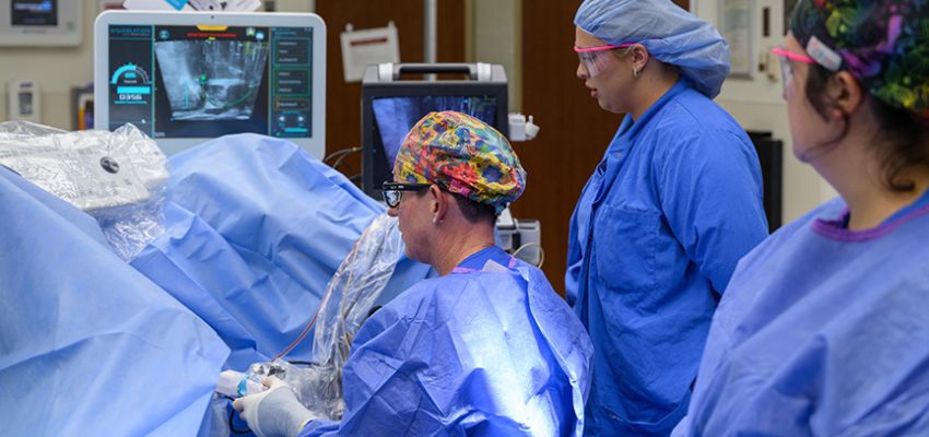 Surgeons and medical staff performing a surgery using advanced imaging technology in an operating room.