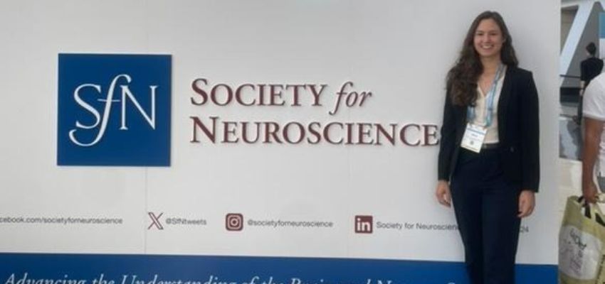 A woman stands in front of a sign at the Society for Neuroscience event.