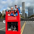 Volunteersstandingonaredobservationplatformatacitymarathonwithskyscrapersinthebackground