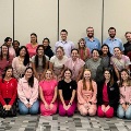 Alargegroupofstudentsandfacultyposetogethermanywearingpinkinsupportofacause