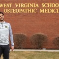 AmanholdingasoccerballstandingoutsidetheWestVirginiaSchoolofOsteopathicMedicinebuilding