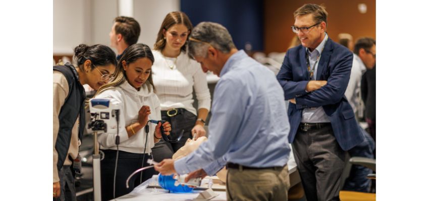 A group of individuals participating in a hands-on medical training session with instructors observing.