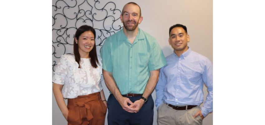 Three individuals stand together indoors, representing collaborative efforts at UNTHSC-TCOM.